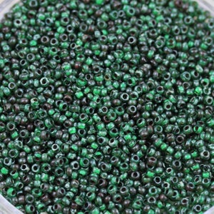 Puede incluir: Una vista de cerca de una gran cantidad de pequeñas cuentas de vidrio redondas de color verde. Las cuentas tienen un acabado ligeramente iridiscente, lo que les da un brillo sutil.