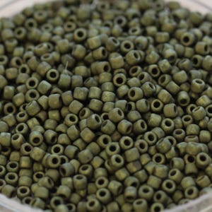 May include: A close-up image of a large quantity of small, round, green glass beads. The beads have a matte finish and are uniform in size and shape.