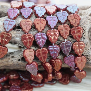 May include: A strand of iridescent glass beads in the shape of leaves. The beads are a deep red color with a subtle shimmer.