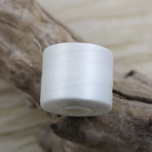 Puede incluir: Una bobina de hilo blanco.