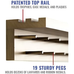 May include: A wooden display shelf with a top rail for trophies, medals, and plaques. The shelf has 19 sturdy pegs for hanging lanyards and ribbon medals. "PATENTED TOP RAIL" and "19 STURDY PEGS" are printed on the image.