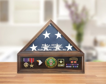 Könnte beinhalten: Eine hölzerne Schattenbox mit einer gefalteten amerikanischen Flagge, einem Namensschild mit dem Text "BRIAN A. GROSSMAN UNITED STATES ARMY MARCH 5, 1992 - APRIL 1, 2023" und einer Auswahl an militärischen Medaillen und Abzeichen.