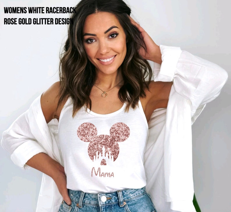 May include: White tank top with a rose gold glitter Mickey Mouse design and the word "Mama" underneath. The Mickey Mouse design features a silhouette of Cinderella's castle inside the ears.