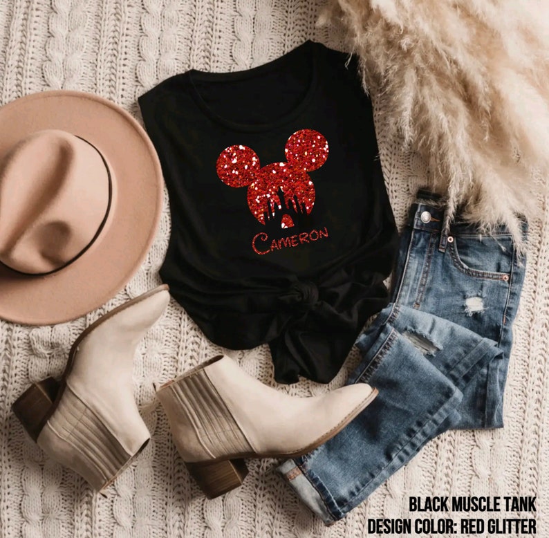 May include: Black sleeveless muscle tank with a red glitter Mickey Mouse head design featuring the silhouette of Cinderella's castle. The name "CAMERON" is written below the design.