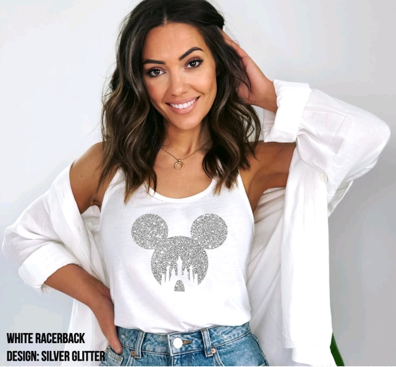 May include: White racerback tank top with a silver glitter Mickey Mouse head design featuring the Cinderella Castle inside the ears. The text "WHITE RACERBACK" and "DESIGN: SILVER GLITTER" is printed below the image.