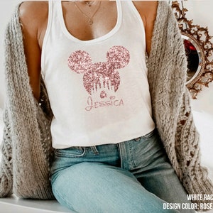 May include: White racerback tank top with a rose gold glitter Mickey Mouse design and the name "Jessica" underneath.
