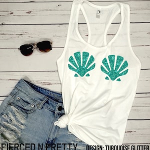 May include: White tank top with a turquoise glitter seashell design. The tank top is paired with denim shorts and sunglasses. The text "Pierced N Pretty" and "Design: Turquoise Glitter" are visible.