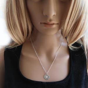 Eine Frau trägt gravierte Kompass-Kette mit Koordinaten.  Die Kette ist aus 925 Silber.