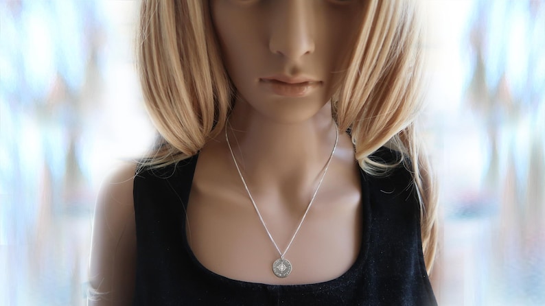 Eine Frau trägt gravierte Kompass-Kette mit Koordinaten.  Die Kette ist aus 925 Silber.