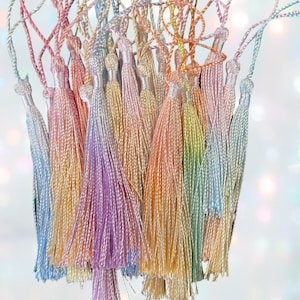May include: A bunch of colorful, iridescent tassels with a gradient of pastel colors, including pink, purple, blue, and green.