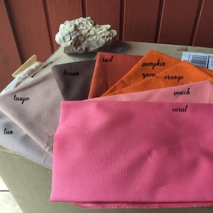 Pu&ograve; includere: Una collezione di campioni di tessuto in varie tonalit&agrave; di arancione, marrone e beige. I campioni sono etichettati con i seguenti colori: beige, tortora, marrone, ruggine, spezie di zucca, arancione, pesca e corallo.
