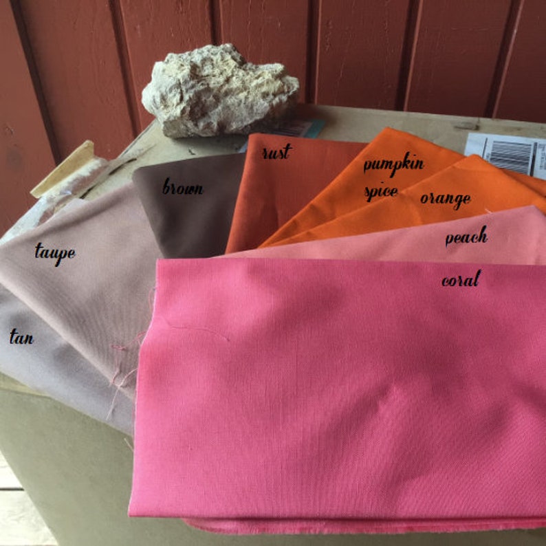 Pu&ograve; includere: Una collezione di campioni di tessuto in varie tonalit&agrave; di arancione, marrone e beige. I campioni sono etichettati con i seguenti colori: beige, tortora, marrone, ruggine, spezie di zucca, arancione, pesca e corallo.