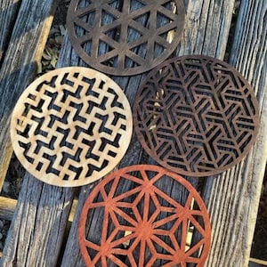 May include: Four wooden coasters with intricate geometric designs. The coasters are in various shades of brown, black, and red.