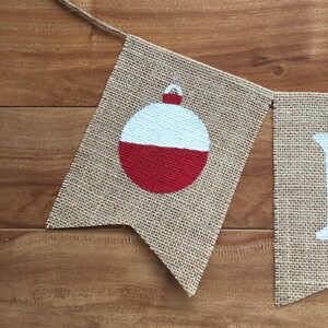 Peut inclure: Une banni&egrave;re en toile de jute avec un flotteur de p&ecirc;che rouge et blanc peint dessus. La banni&egrave;re fait partie d'une banni&egrave;re plus grande qui dit "Fish On".