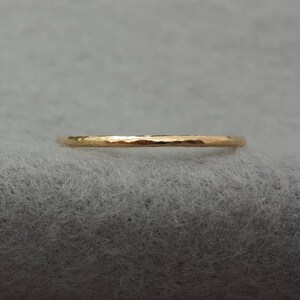 May include: A thin gold band ring with a hammered texture.
