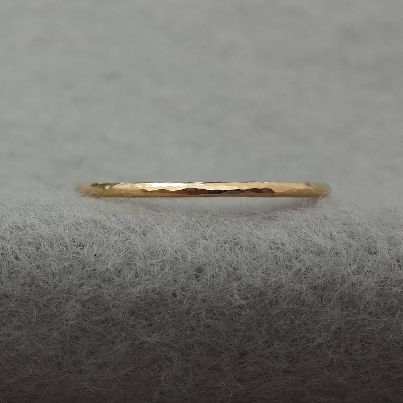 May include: A thin gold band ring with a hammered texture.