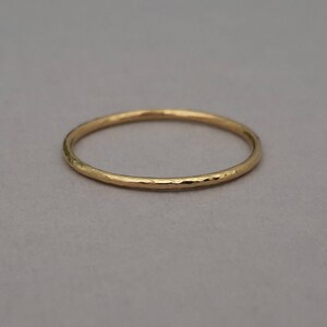 May include: A thin gold band ring with a hammered texture.