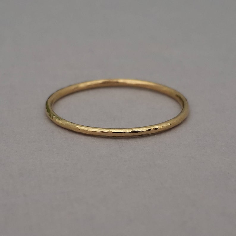 May include: A thin gold band ring with a hammered texture.