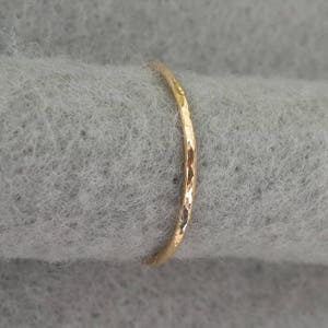 May include: A thin gold band ring with a hammered texture.