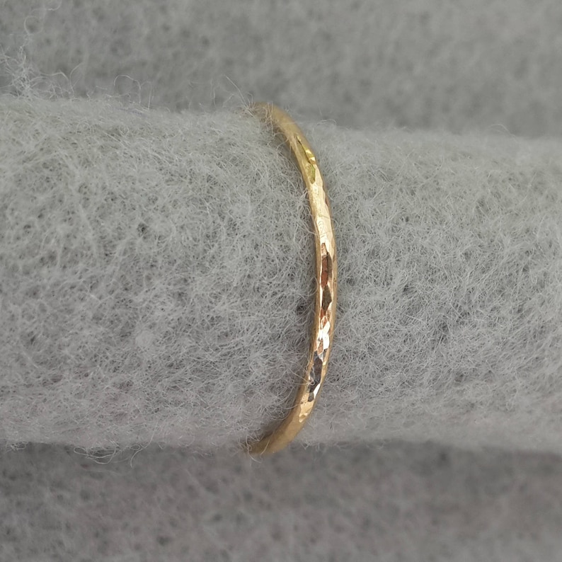 May include: A thin gold band ring with a hammered texture.