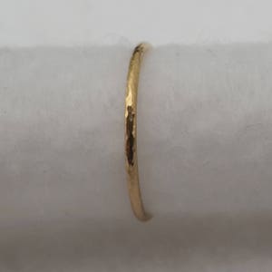May include: A thin gold band ring with a hammered texture.