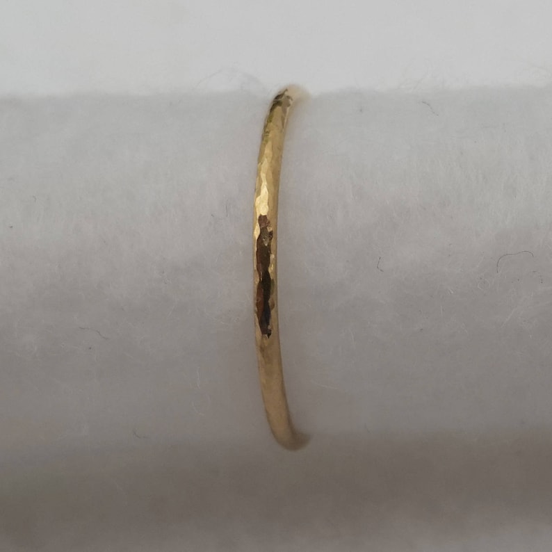 May include: A thin gold band ring with a hammered texture.