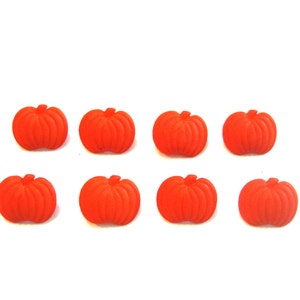 May include: Eight small, orange pumpkin decorations arranged on a white background. Each pumpkin has a ribbed texture and a small stem. Perfect for fall-themed crafts or decor.
