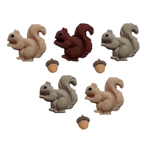 May include: A collection of decorative squirrel and acorn embellishments in various shades of brown and gray. The squirrels have fluffy tails and are posed in a playful manner. The acorns are small and detailed.
