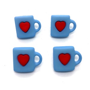 May include: Four light blue mug-shaped embellishments, each featuring a red heart. The mugs have a handle on the right side. These small, decorative items are likely used for crafts or scrapbooking projects.