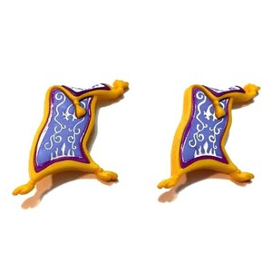 May include: Two miniature, yellow and purple magic carpet figurines. Each carpet has a blue center with white decorative swirls and a purple border. The carpets are curled at the ends, giving them a whimsical appearance.