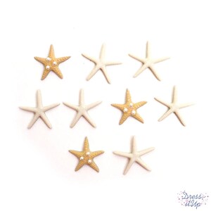 May include: A collection of nine starfish embellishments in varying shades of cream and tan, some adorned with small, pearl-like beads. The starfish are arranged on a white background, perfect for craft projects.