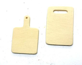 May include: Two small, unfinished wooden cutting boards. One has a handle with a hole, the other has a rectangular opening. Both are light beige in color and have visible wood grain.