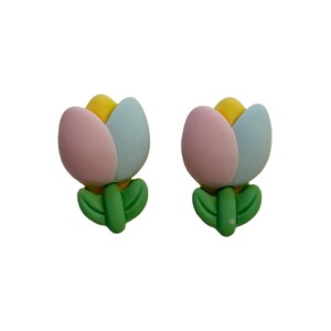 May include: A pair of tulip-shaped earrings. Each earring features a yellow center, pink and light blue petals, and green leaves. The earrings are designed to resemble a spring flower.