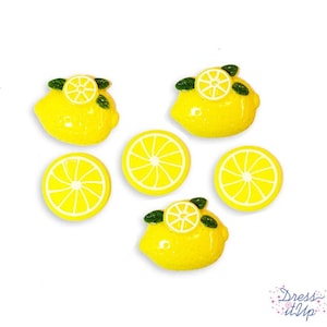 May include: Bright yellow lemon-shaped embellishments with white details and green leaves. The image shows several lemon slices and whole lemons, perfect for crafting or decorative purposes. The lemons are arranged on a white background.