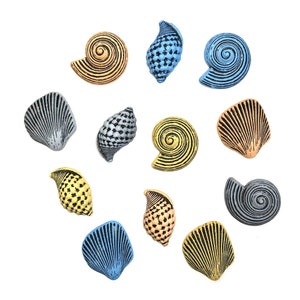 May include: A collection of decorative seashell ornaments in various shapes and colors. The shells include spiral, fan, and conch designs, with colors like gold, blue, silver, and yellow. The shells are arranged on a white background.