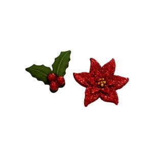 May include: Two Christmas-themed decorations on a white background. One is a red glitter poinsettia with yellow center. The other is a holly sprig with green leaves and red berries. Festive holiday decor.