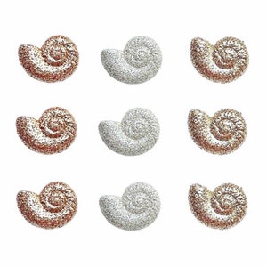 May include: Nine decorative seashell-shaped objects. The objects are arranged in three rows of three. Six are a copper color with white glitter, and three are silver with white glitter. All are on a white background.