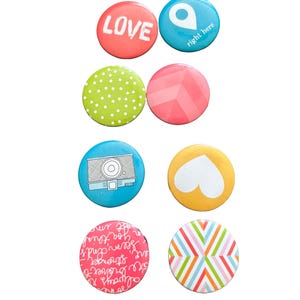May include: A collection of eight round buttons with various designs and colors. The buttons include the word "LOVE" in red, a blue button with a location icon and the words "right here", and other patterned and graphic designs.