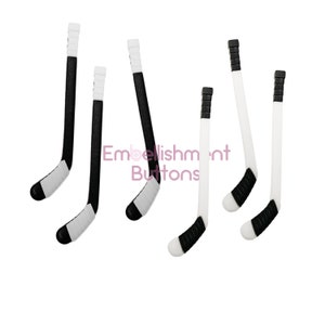 May include: A collection of hockey stick embellishments. The sticks are black and white with black grips and white tape. The text "Embellishment Buttons" is in the image.