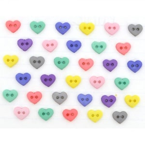 May include: A collection of heart-shaped buttons in various colors, including pink, green, blue, yellow, purple, and gray. Each button has two holes for sewing. These small, colorful buttons are ideal for craft projects and adding a decorative touch to clothing.