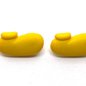 May include: Two bright yellow, rounded shoe-shaped objects with a smaller, raised yellow detail on top. The objects are set against a plain white background, creating a clean and simple presentation.