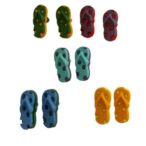 May include: A collection of colorful flip-flops in various shades, including green, orange, purple, blue, and yellow. Each pair features a polka dot pattern. The flip-flops are arranged on a white background.