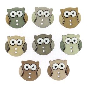 May include: A collection of eight owl-shaped buttons in various shades of brown, beige, and green. Each button features large white eyes, a small beak, and two small holes for sewing. The buttons are made of a smooth, matte material.