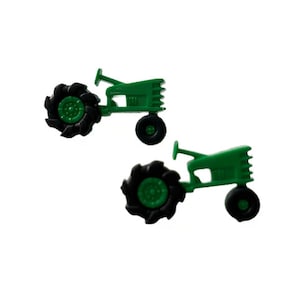 May include: Two green toy tractors with black wheels are displayed against a white background. The tractors have a classic design, with a detailed body and large rear wheels. The image is well-lit, highlighting the vibrant green color.