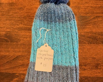 Gorro de punto a mano con rayas brillantes y pompón.
