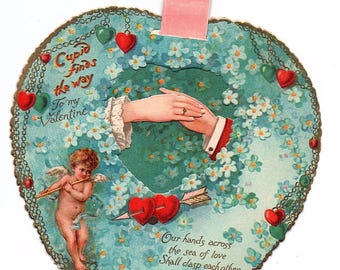 Biglietto di San Valentino meccanico degli anni '10 — Cartolina tedesca di E.P. Dutton, scena di Cupido con cambio di mani, trasformazione tramite linguetta