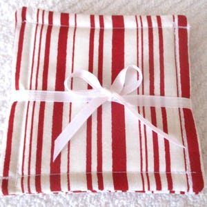 Puede incluir: Conjunto de posavasos de tela a rayas rojas y blancas, atados con una cinta blanca.