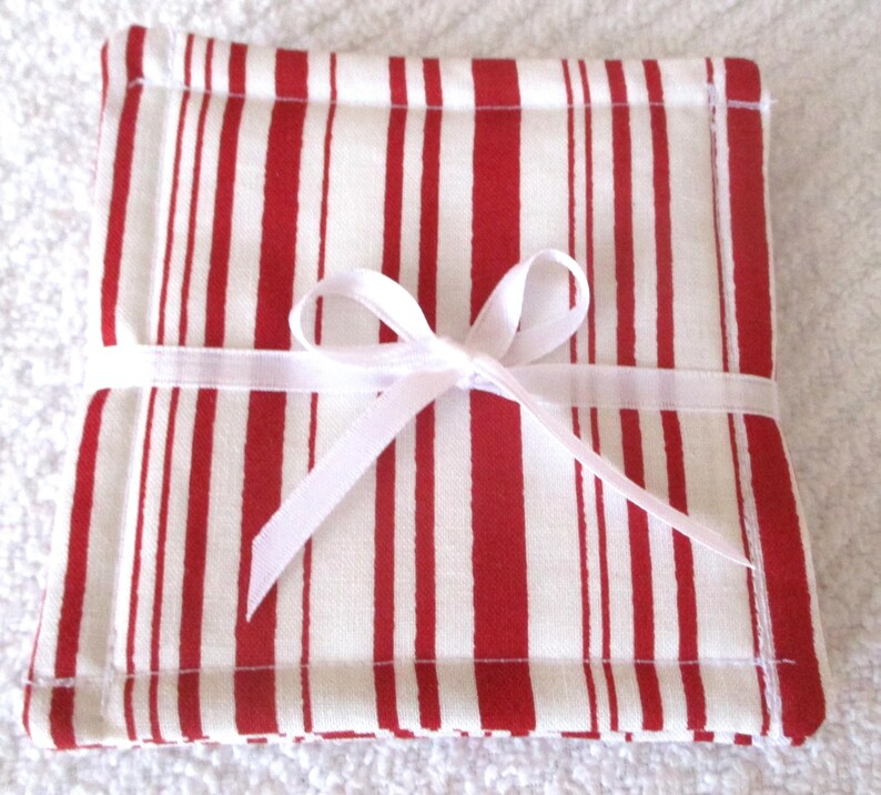 Puede incluir: Conjunto de posavasos de tela a rayas rojas y blancas, atados con una cinta blanca.