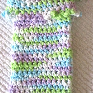 May include: A crocheted washcloth with a loop handle. The washcloth is made with a multi-colored yarn in shades of white, light blue, light green, and lavender.