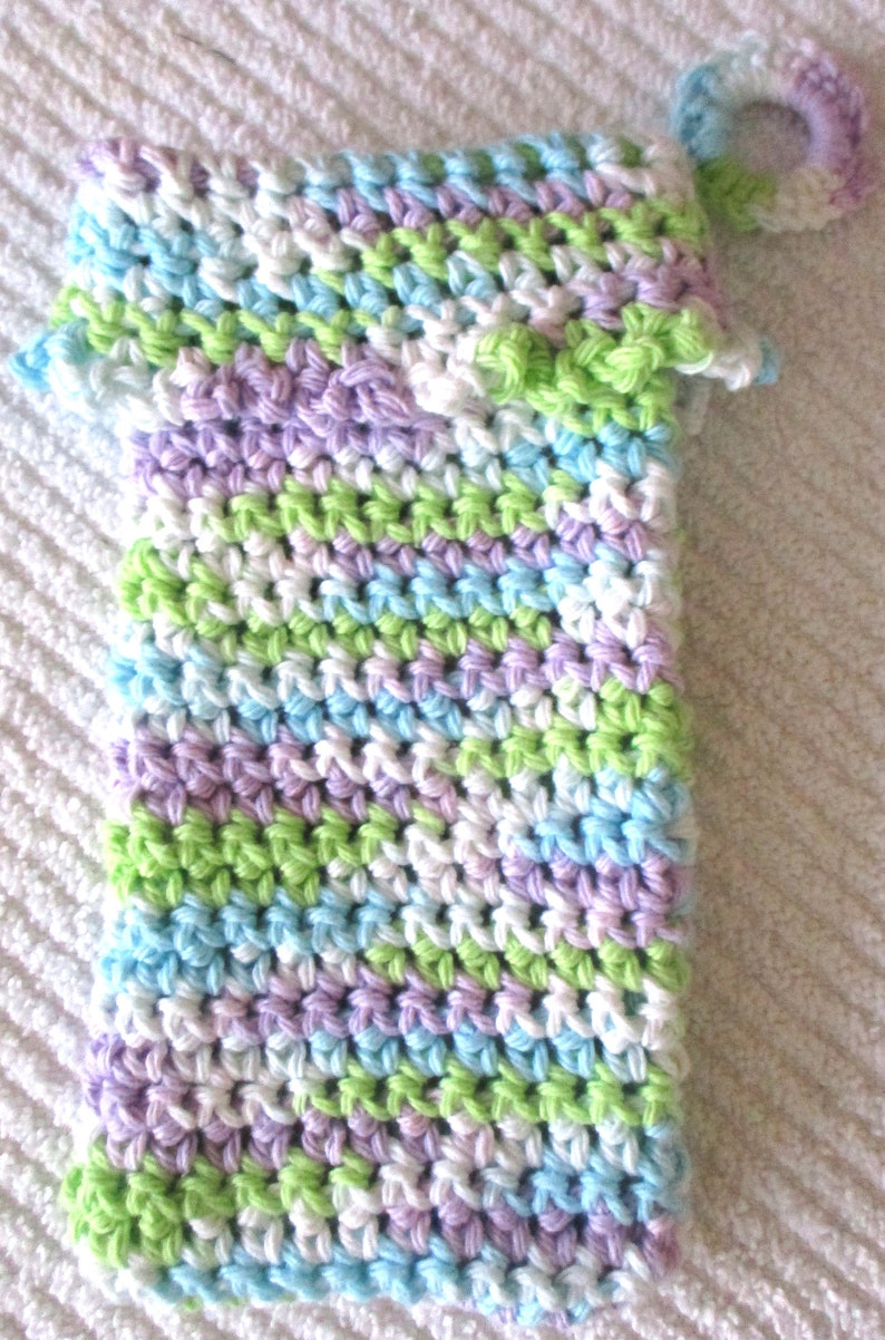 May include: A crocheted washcloth with a loop handle. The washcloth is made with a multi-colored yarn in shades of white, light blue, light green, and lavender.